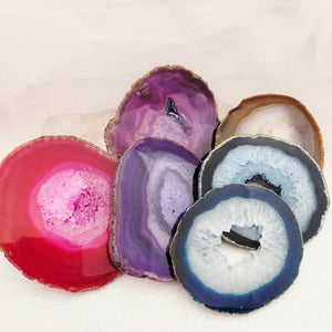 Large dyed agate slices showing translucent banded stone with natural wavy edging on a surface.