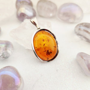 Oval amber pendant in sterling silver wavy split bezel setting with bail