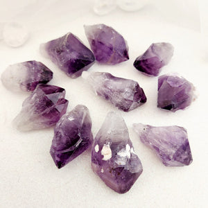 Small natural amethyst point with soft purple tones and raw form