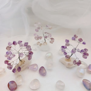 Amethyst tumbled stone tree displayed on a natural quartz cluster base