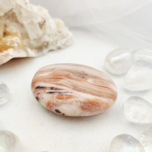 Smooth oval pink calcite palm stone with striped natural banding.