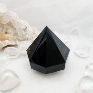 Faceted black obsidian diamond with sharp angular geometric point.