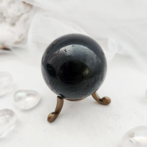 Deep black sphere with glossy finish resting on a bronze stand.