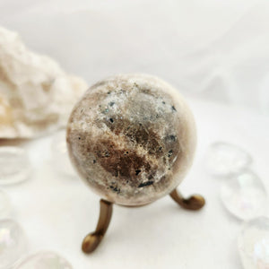 Speckled caramel moonstone sphere resting on a slender bronze stand.