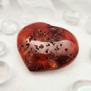 Polished carnelian heart with rich red-orange tone and dark speckling