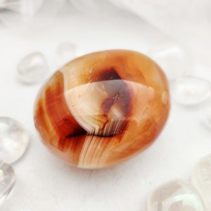 Smooth carnelian palm stone with warm orange and honey banding