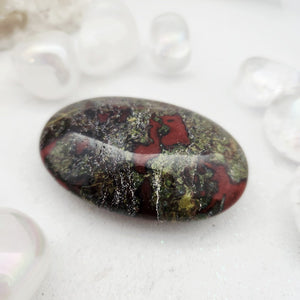 Smooth oval dragon stone palm stone with deep red and green patterning.