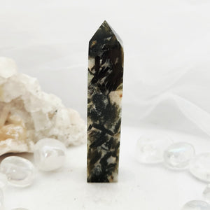 Tall obelisk with faceted tip and dense dark green mineral inclusions.