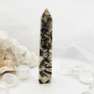 Tall obelisk with faceted tip and scattered dark green inclusions.