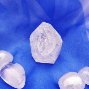 Clear quartz point with rounded faceted top and jagged base edges.