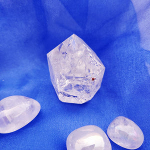 Clear quartz point with faceted crystal formation and jagged edges.