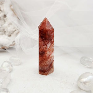 Polished fire quartz point with a faceted top and warm reddish tone