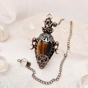 Ornate silver-caged pendulum with golden tiger's eye teardrop stone.