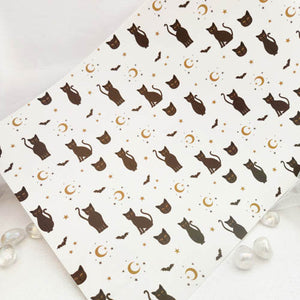 White dinner mat with black cats, gold crescent moons and bats design