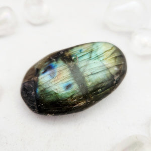 Smooth labradorite palm stone with a dark edge and bright green flash