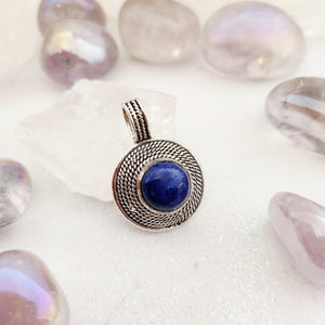 Round lapis lazuli pendant surrounded by five rows of twisted silver-toned wirework with decorated bail