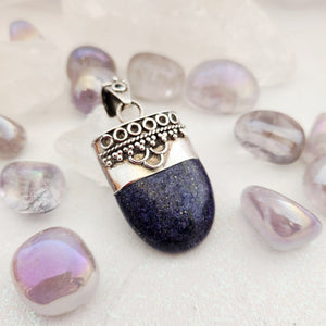 Lapis lazuli half-oval pendant with ornate silver-toned wirework cap and bail