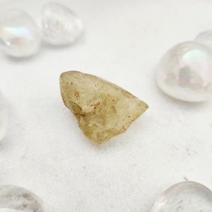 Raw Libyan desert glass piece with a pale yellow, rounded shape