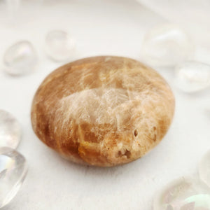 Smooth peach moonstone palm stone with warm golden-orange tones
