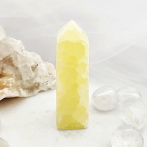 Tall pineapple calcite obelisk with faceted tip and sunny yellow tone.