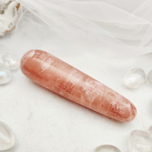 Polished pink calcite wand with a smooth, elongated rounded shape