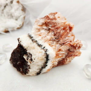 Raw rainbow calcite specimen with layered white, black and peach bands