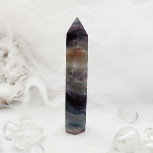 Polished rainbow fluorite point with tall faceted form and banded colour