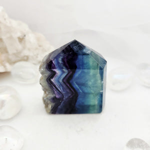 Faceted rainbow fluorite point with a rough pale calcite edge.