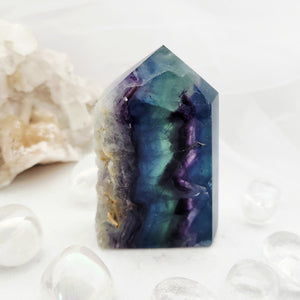 Faceted rainbow fluorite point with a rough pale calcite edge.