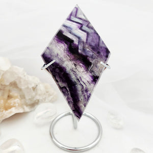 Diamond-shaped fluorite slab displayed upright on a silver ring stand.