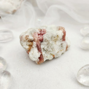 Raw specimen with thin pink tourmaline veins running through white quartz