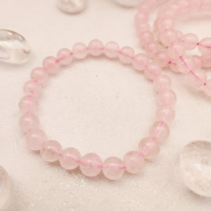 Round pale pink rose quartz beads strung into a stretch bracelet.