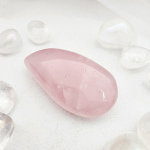 Smooth rose quartz palm stone with a soft pink, teardrop shape