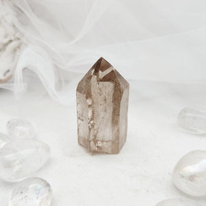 Polished smoky quartz point with a faceted top and light smoky tone