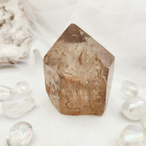 Polished smoky quartz point with a faceted top and warm brown tone