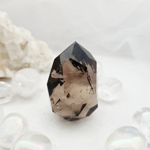 Faceted smoky quartz point with multiple angular cut surfaces.