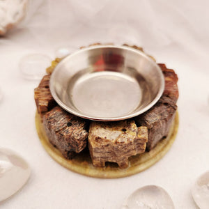 Round soapstone burner with carved elephants encircling a metal bowl.